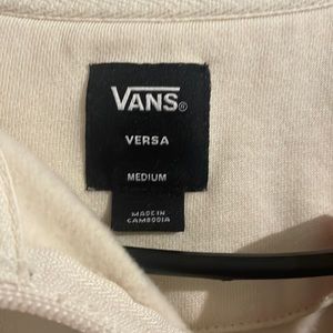 This is a vans cream colored coat with checkers along both sides of the sleeves.